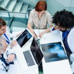 Group of doctors in white coats sitting together at a table reviewing xrays on their computers Oceania University of Medicine